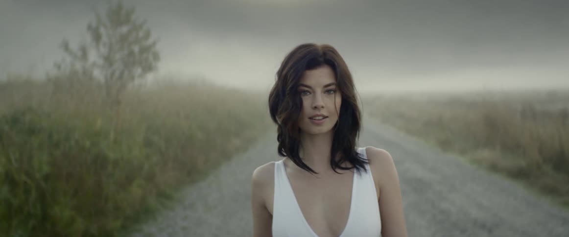 A woman walks down a gravel road and turns around