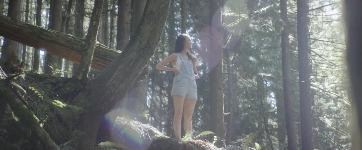 A woman is standing outdoors in a forest area