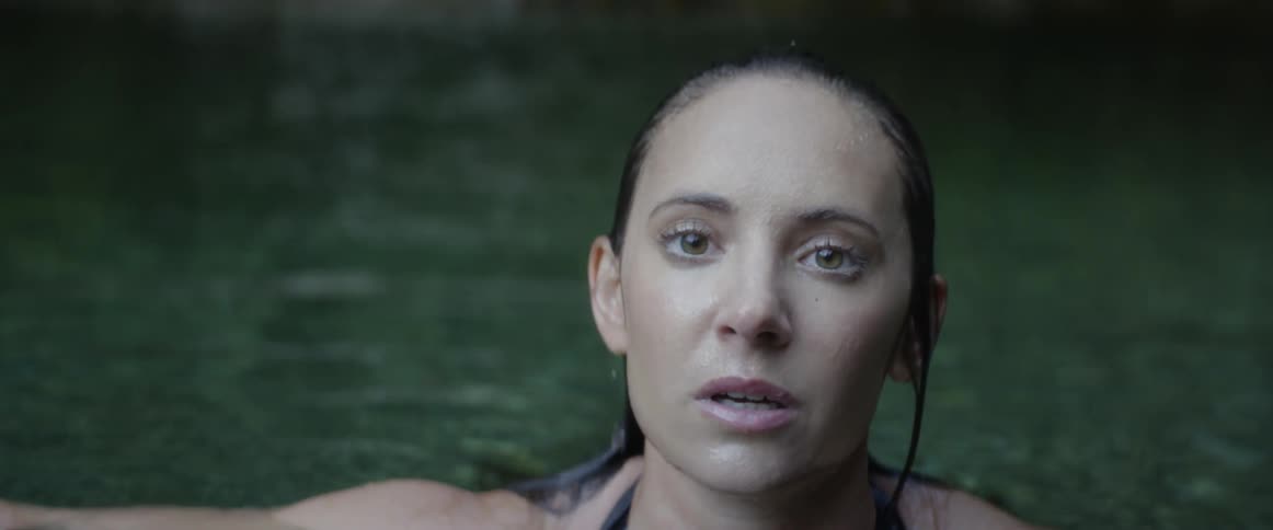 Woman rises from water wiping her hair back