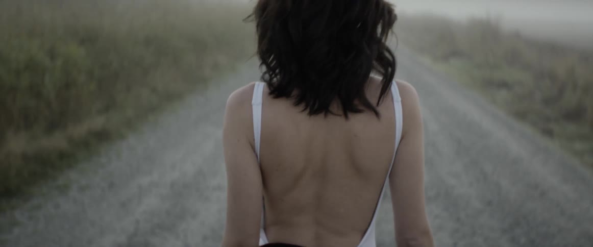 A woman is walking outdoors down a road
