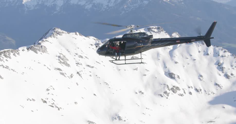 A helicopter flying over a snowy mountain ridge