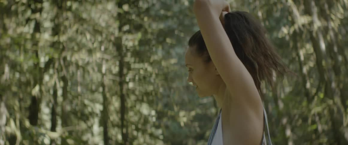 Woman combs her hair into a pony tail while standing outdoors