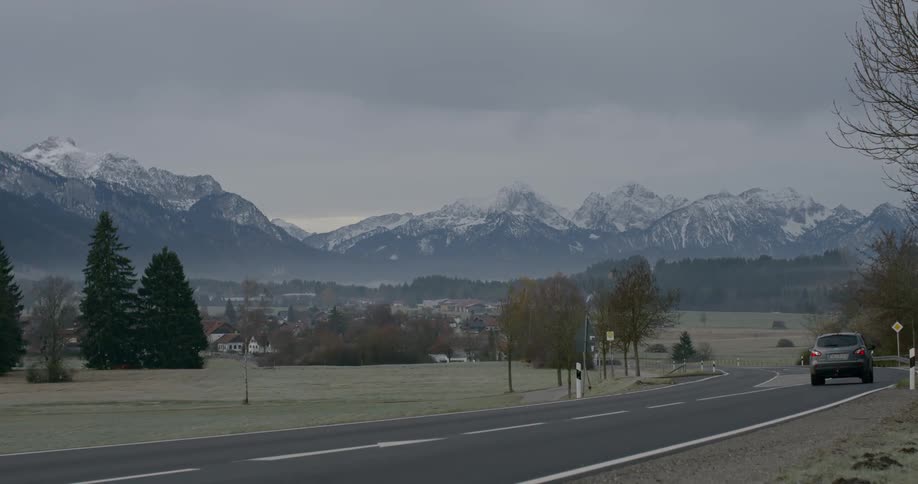 Cars driving down a road near a mountain town