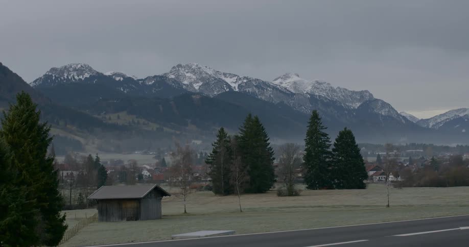 A small shed sits on the field by the mountains