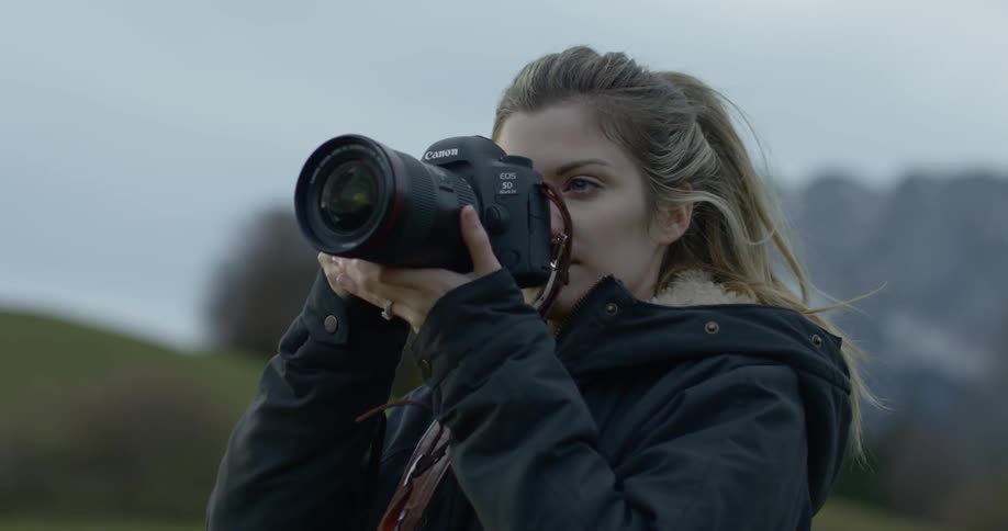 A photographer looks through her camera on a windy day