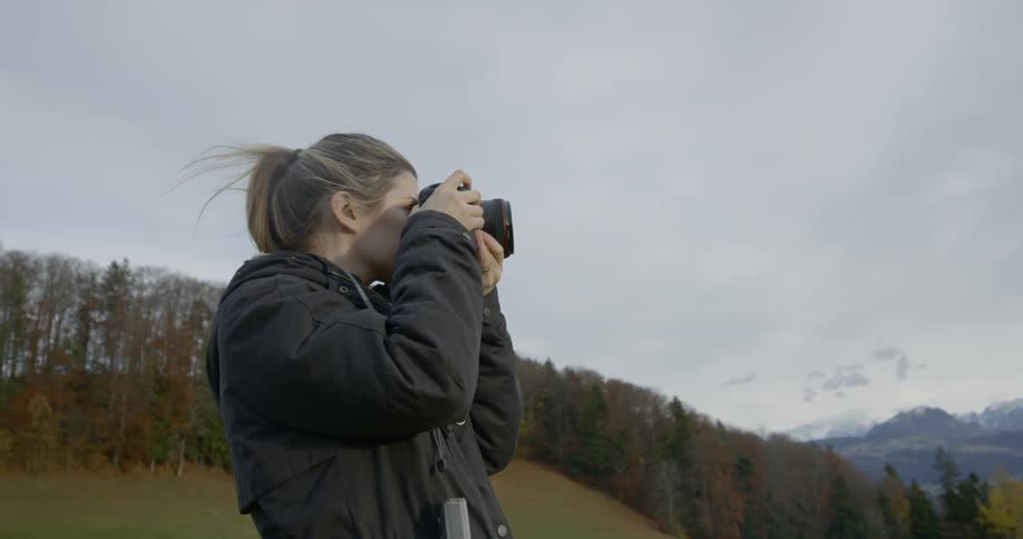 Blonde woman takes landscape photos outdoors