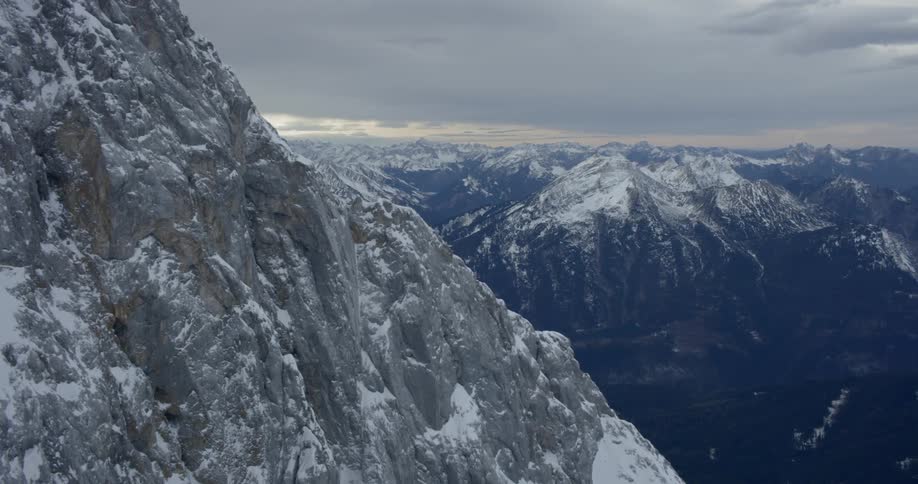 Snow covered mountains sit under a cloudy sky