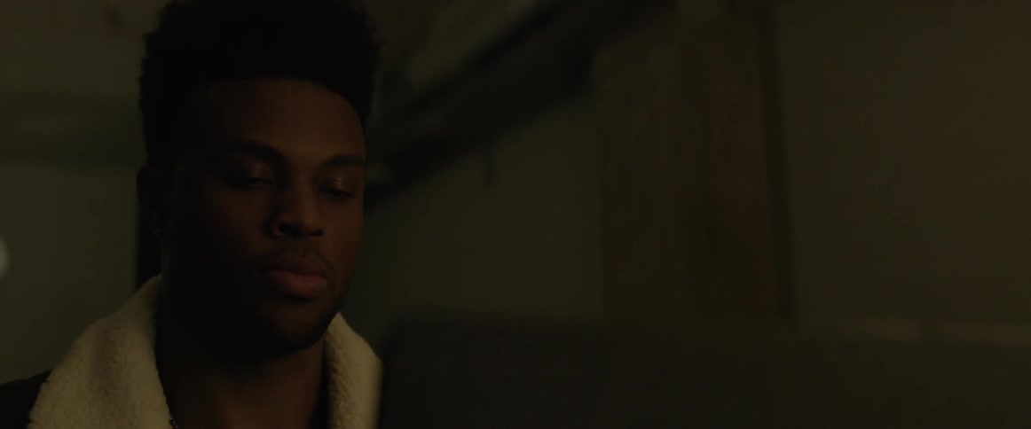 A black man works on a laptop and puts headphones on