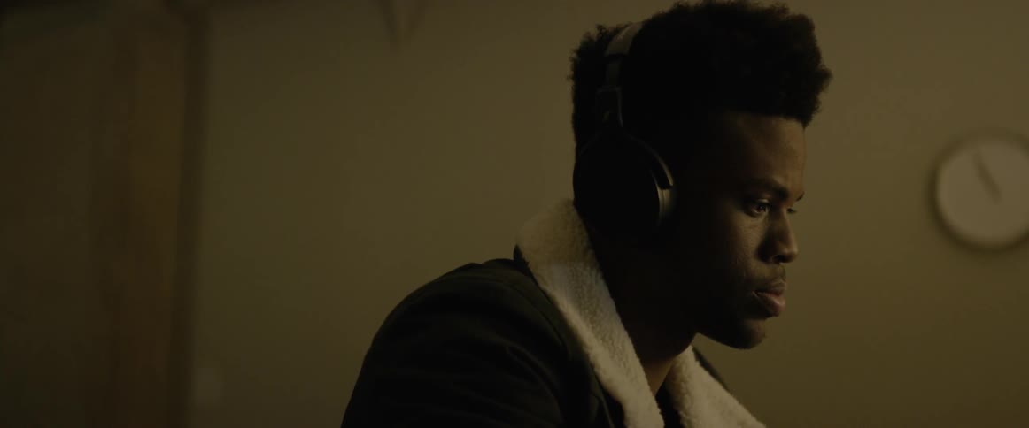 A man listens to something on headphones in a dark room