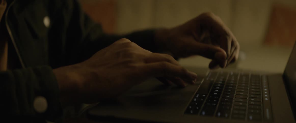 Man sitting at the table uses laptop at night