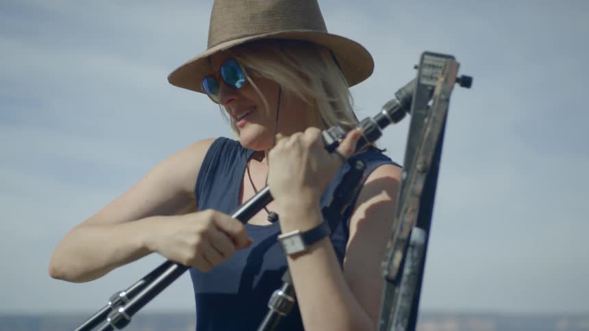 A woman in a hat sets up her easel and canvas to paint