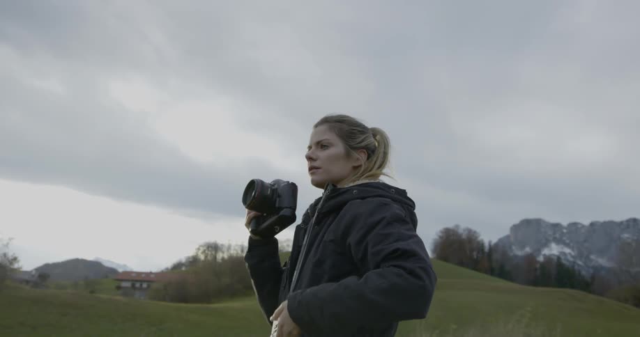 A woman works with photography equipment, light meter and camera