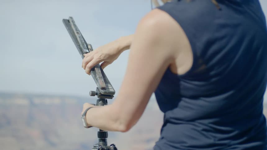 A white woman sets up a tripod outdoors