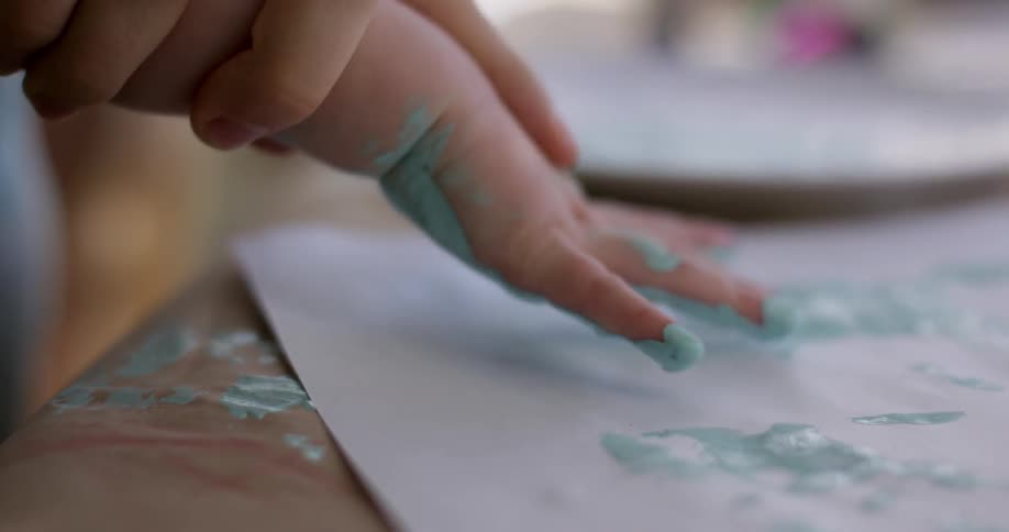 A child is finger painting on a piece of paper