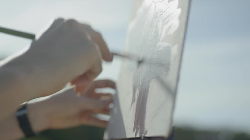 A person painting a tree on a canvas outdoors
