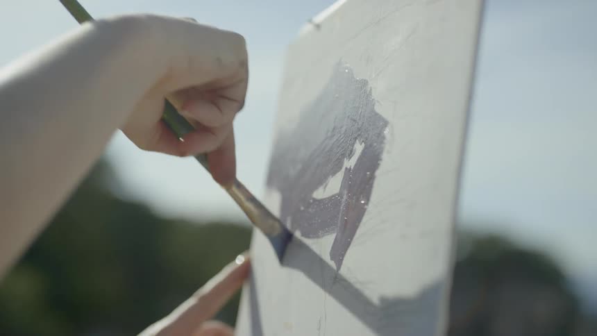 Person paints on thin canvas outdoors during the day