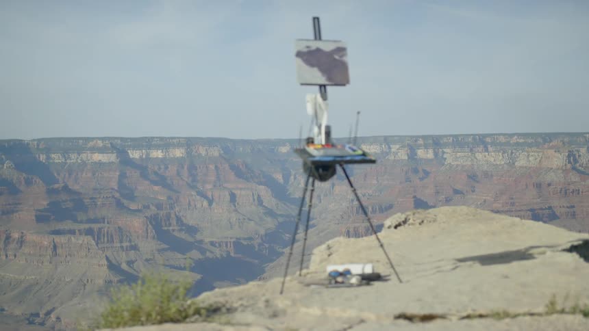 An easel is set up with paints on the cliff
