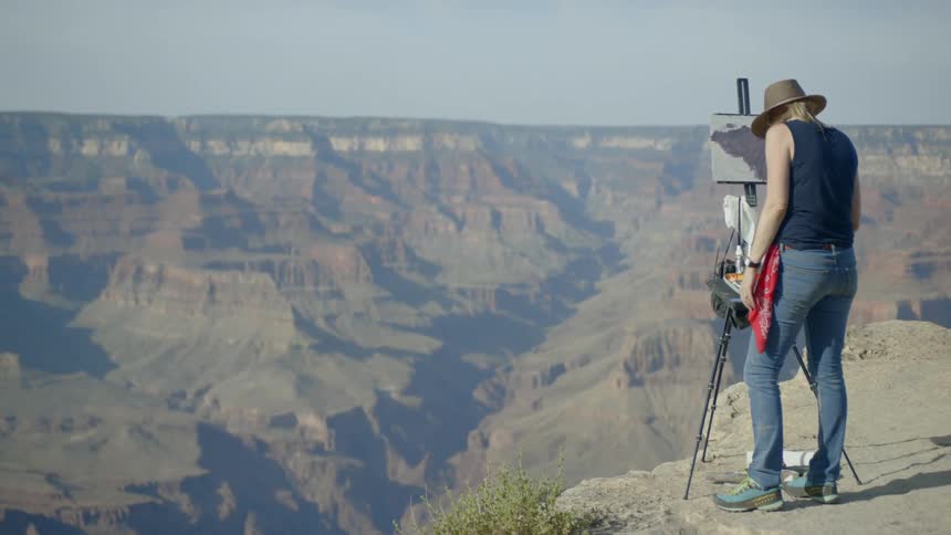 A female painter painting at the cliff