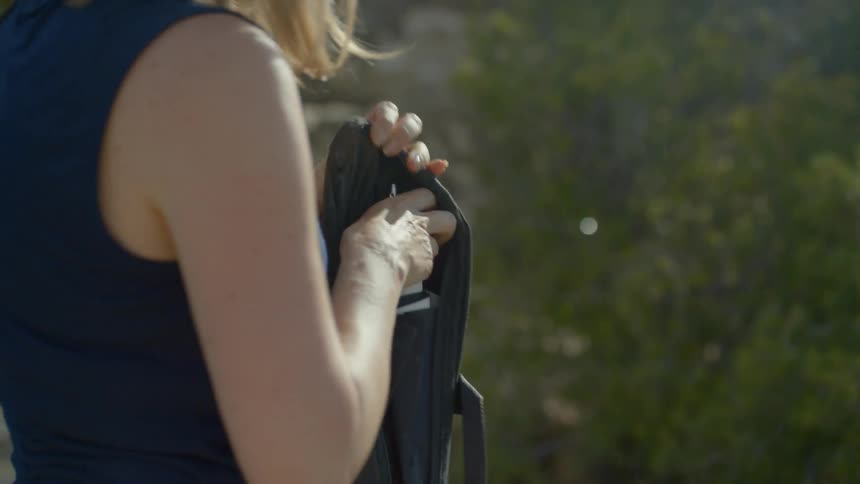 A woman standing outside unzipping a bag with photo equipment