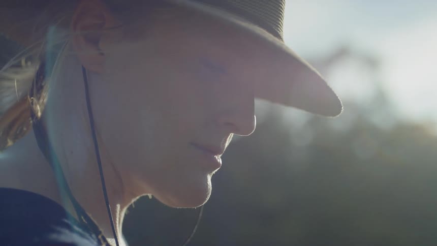 Close up of woman wearing a hat breeze blowing through her hair standing outdoors