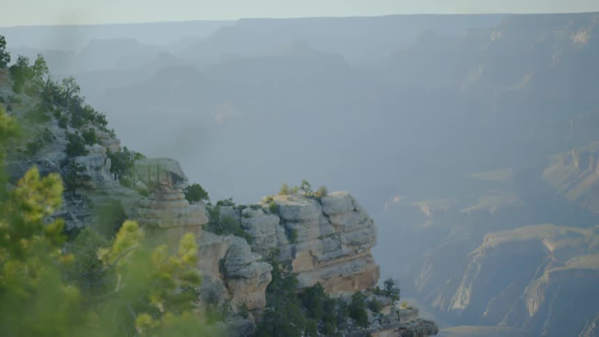 Mountain and cliff dotted with vegetation on cloudy foggy day