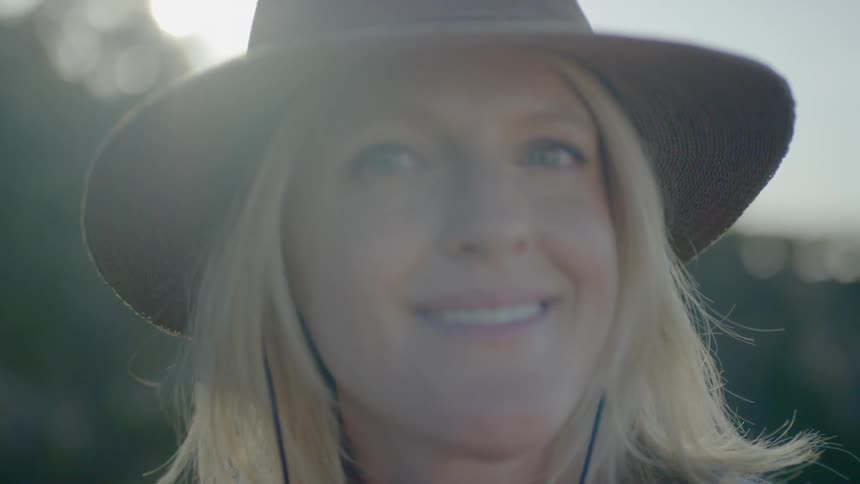 A blonde haired woman wearing a hat smiles for the camera