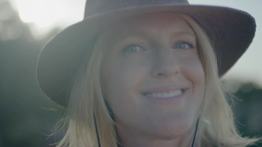 A woman smiles outside on a windy day