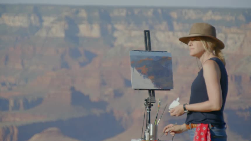Artist glance around canyon as she stands in front of easel