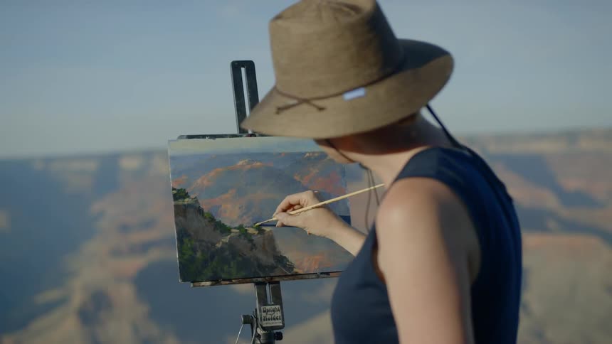 A female painter painting at the canyon