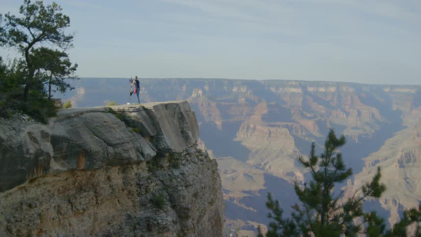 A person is painting on a canvas at the top of a mountain thats overlooking a canyon