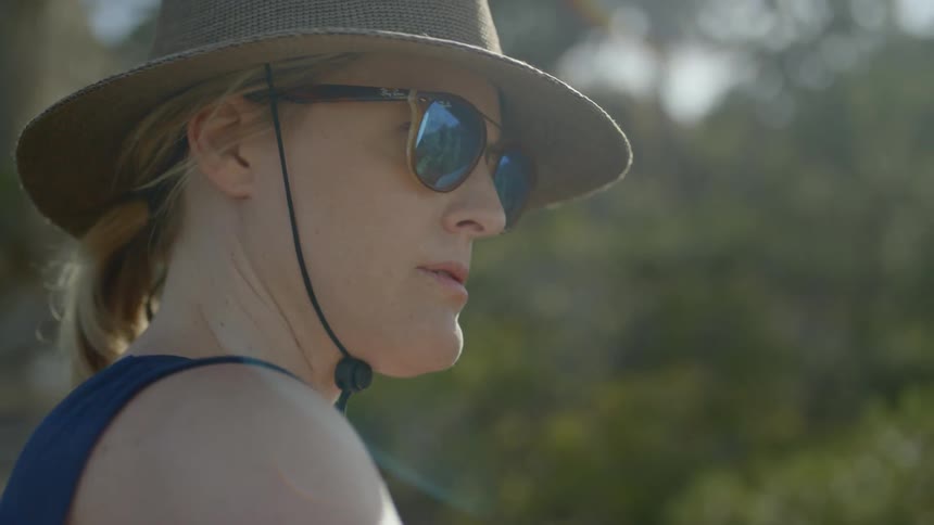 A woman wearing sunglasses paints outside