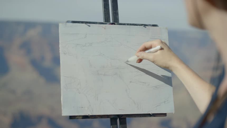 A female painter painting at the mountain peak