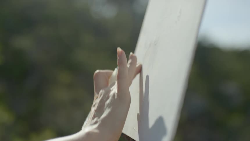An artist using a finger to smudge a canvas before drawing