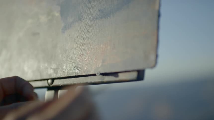 An artist paints on canvas while outdoors