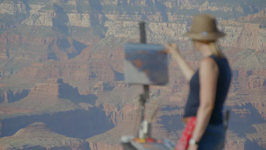 A woman in a hat sets up her easel and canvas to paint