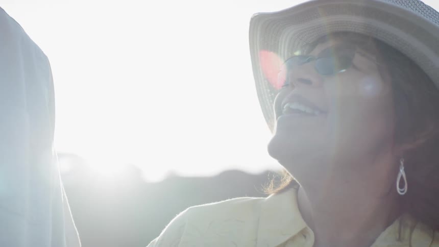A woman and a man standing outside talking with the sun in the background