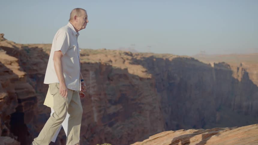 An elderly couple walk to the top of a rocky canyon
