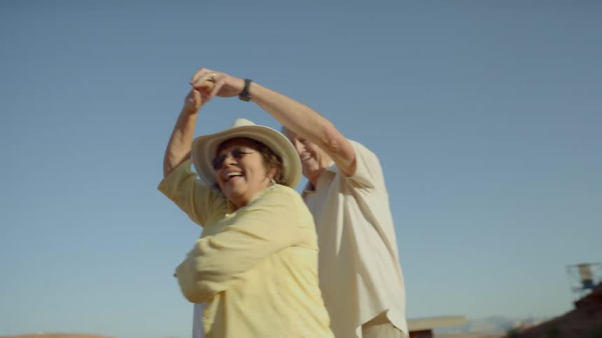 Older couple laughing and dancing outdoors in the mountains