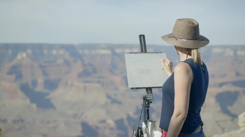 A woman is painting outdoors
