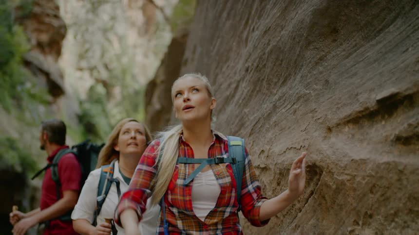 A woman leading a hiking group pauses to point up