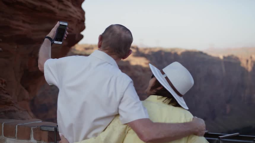 A man and a woman standing by a canyon taking a picture