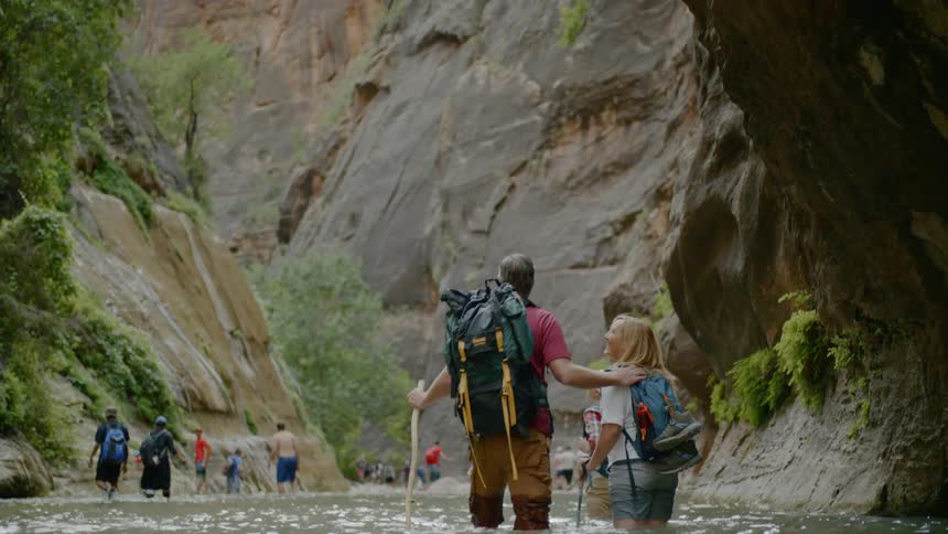 People hike in groups through the water in the canyon