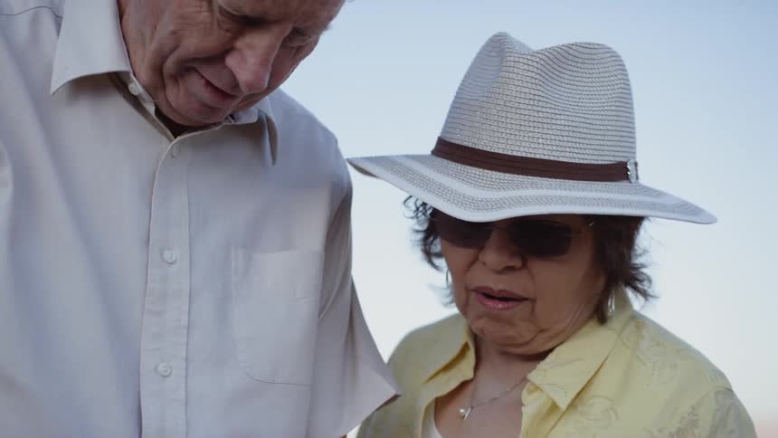 A man and a woman standing outside looking at a smart phone