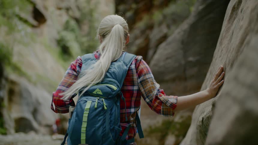 A woman hikes through a river and pauses to take in the scenery