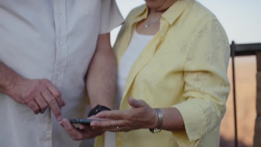A man and a woman standing by a canyon looking at a smartphone