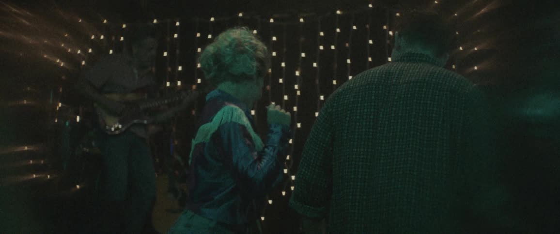 A blonde woman dances with a man in a dark bar