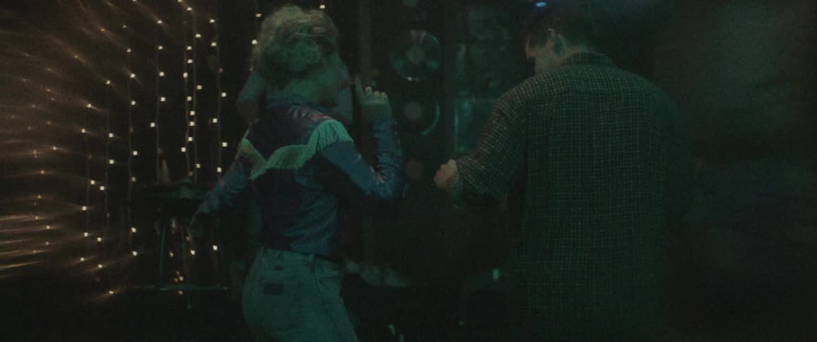 A woman shows a man how to line dance in a bar