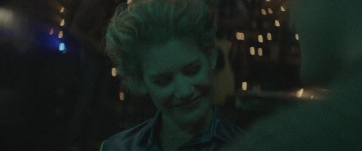 A man walks up to a woman in a bar and she tilts her head and smiles