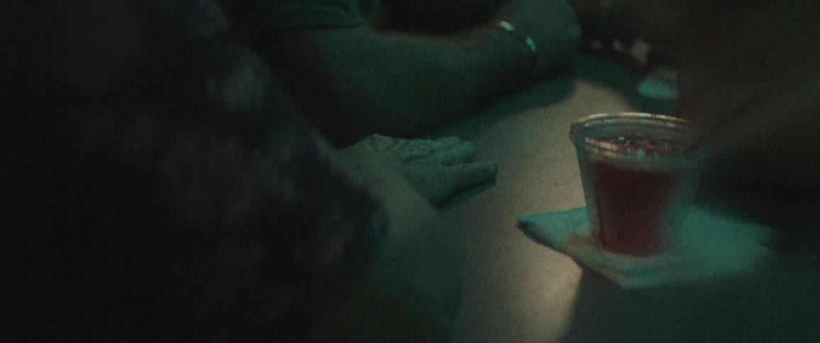 A man taps on the table with his hand next to a full drink
