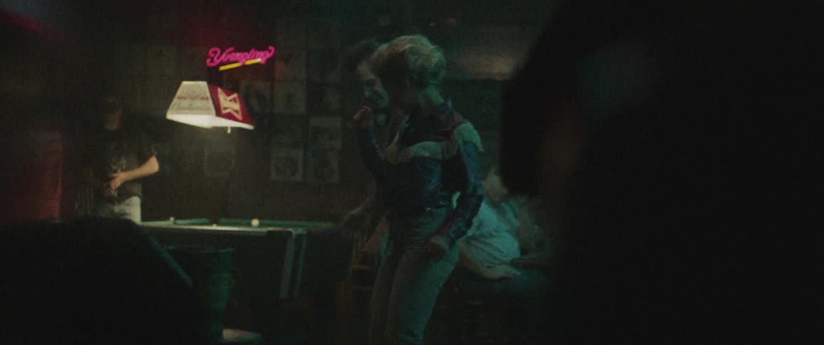 A woman dances with a guy near a pool table